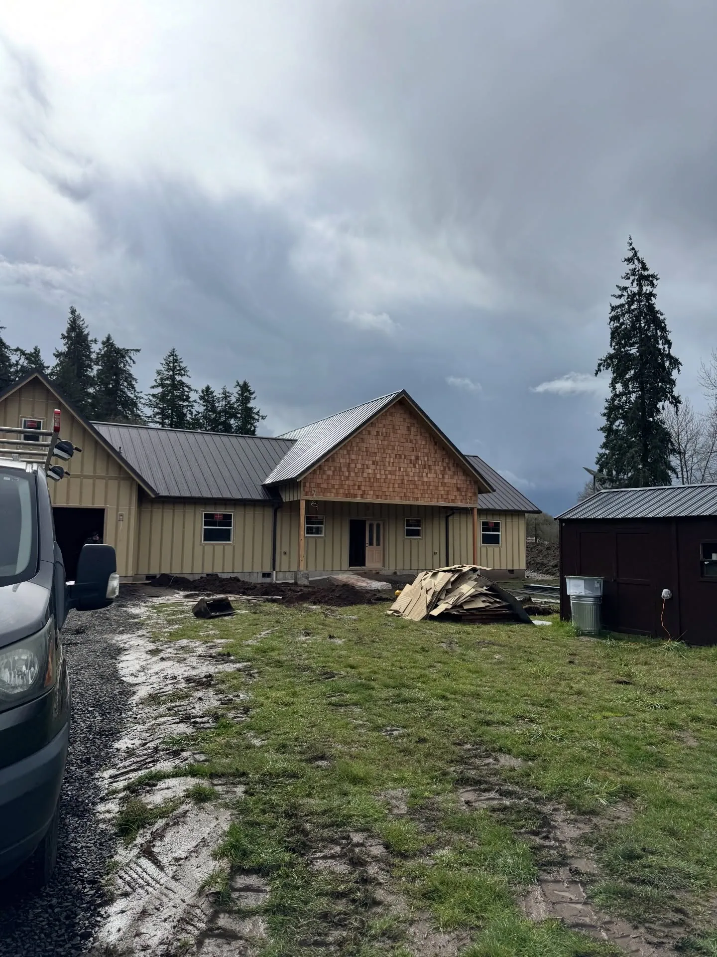 A finished board-and-batten home with a metal roof under a stormy sky