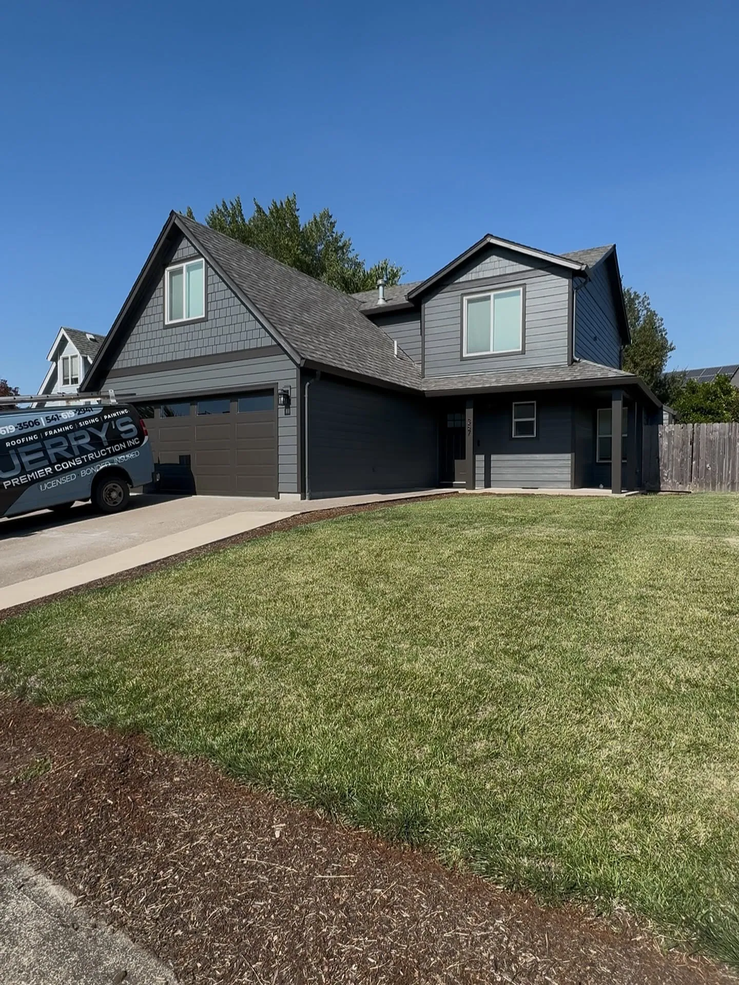 A finished two-storey home in charcoal siding with the Jerry's van in the driveway