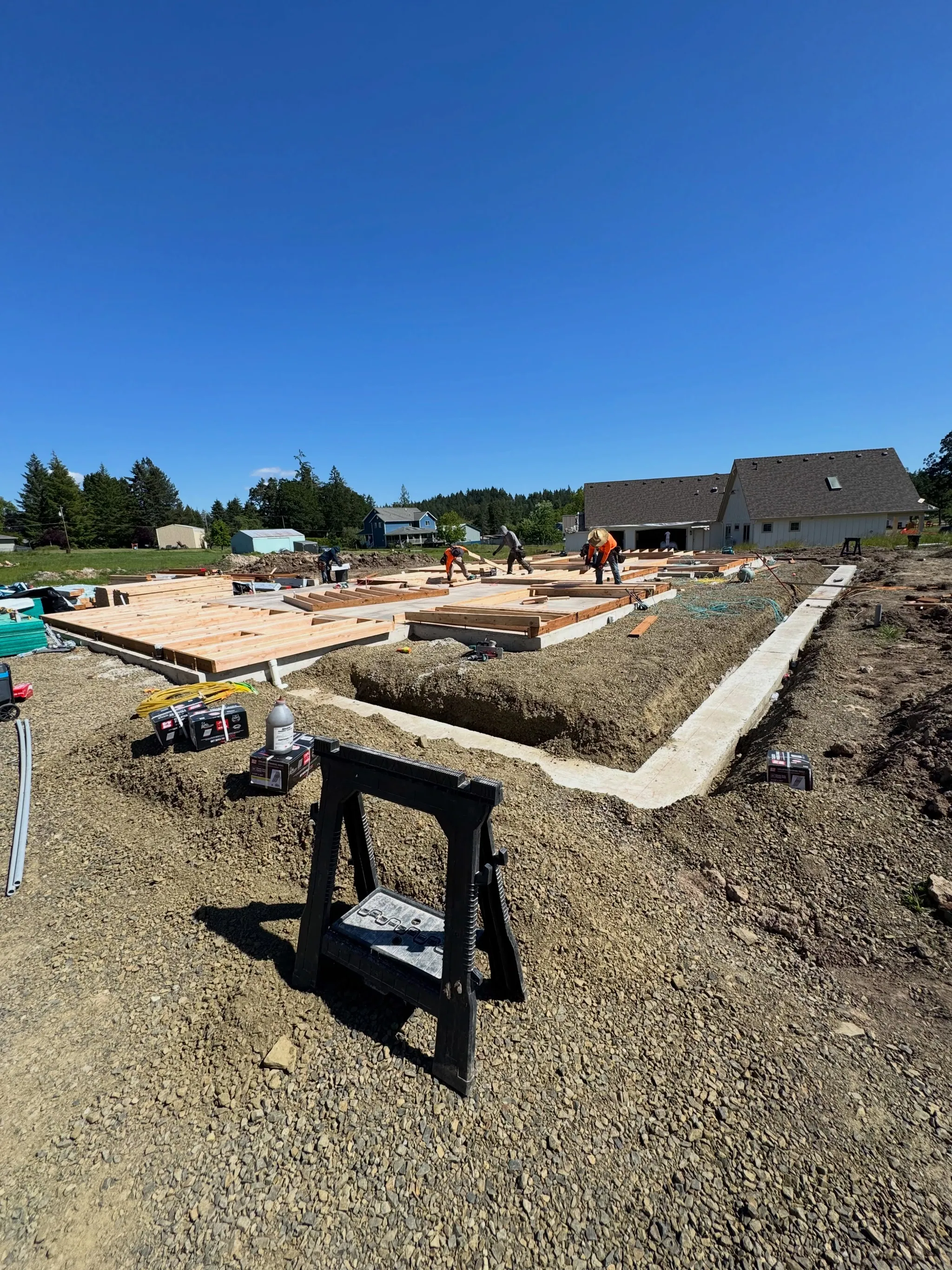 Crew setting foundation forms on a new home site, sawhorse and tools in the foreground