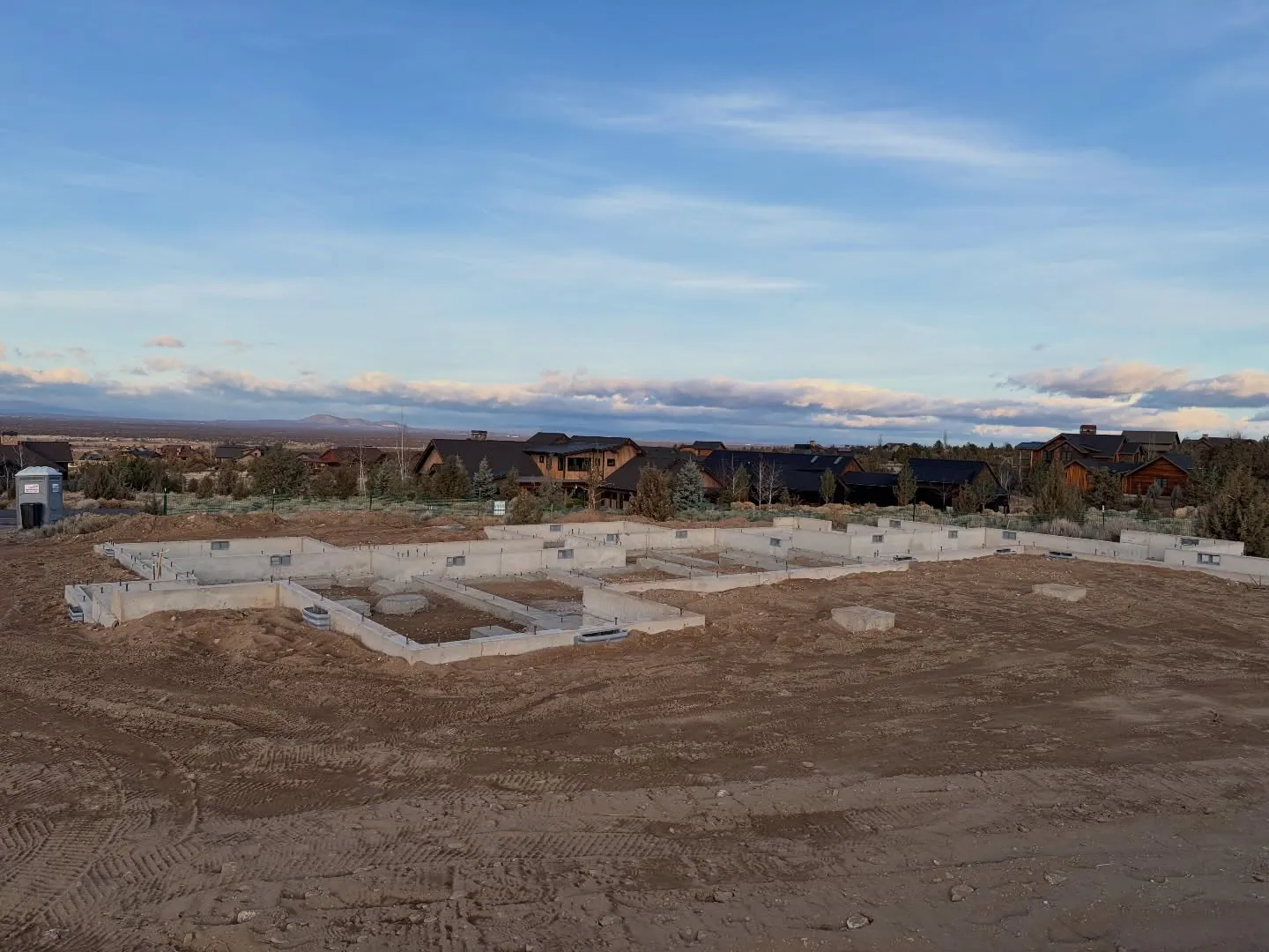 Concrete stem walls of a new custom home foundation on a cleared lot at sunset